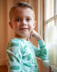 Little Boy wearing Blue two-piece pajama set with vintage Christmas holly pattern made with pima cotton