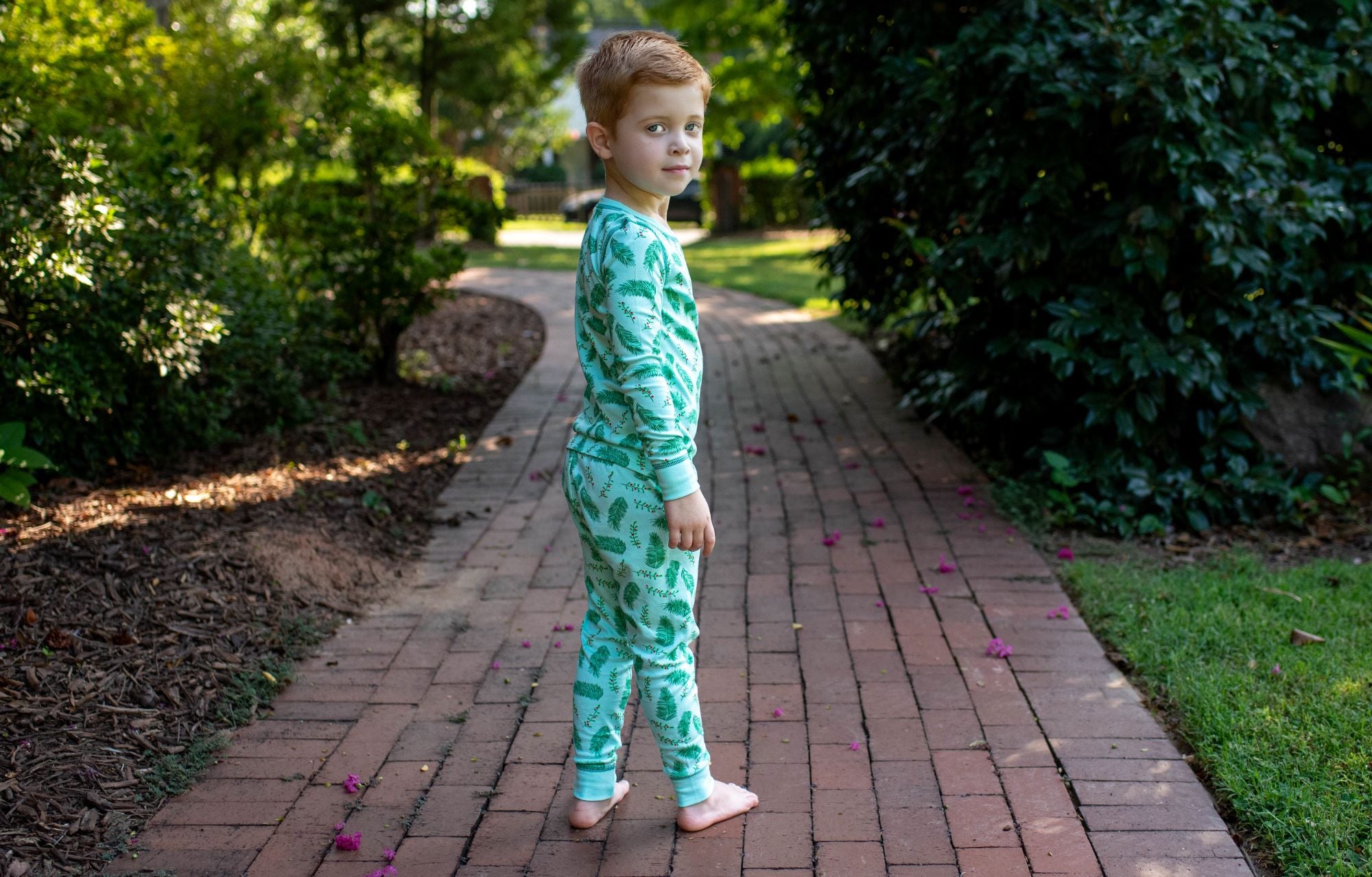 Little Boy Blue wearing two-piece pajama set with vintage Christmas holly pattern made with pima cotton