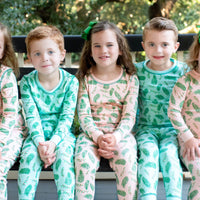 Children wearing Pink and Blue two-piece pajama sets with vintage Christmas holly pattern made with pima cotton