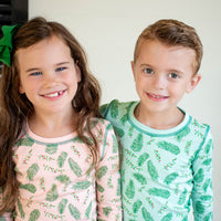Children wearing Pink and Blue two-piece pajama sets with vintage Christmas holly pattern made with pima cotton