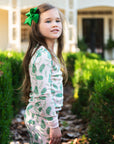 Little Girl wearing Pink two-piece pajama set with vintage Christmas holly pattern made with pima cotton