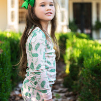 Little Girl wearing Pink two-piece pajama set with vintage Christmas holly pattern made with pima cotton