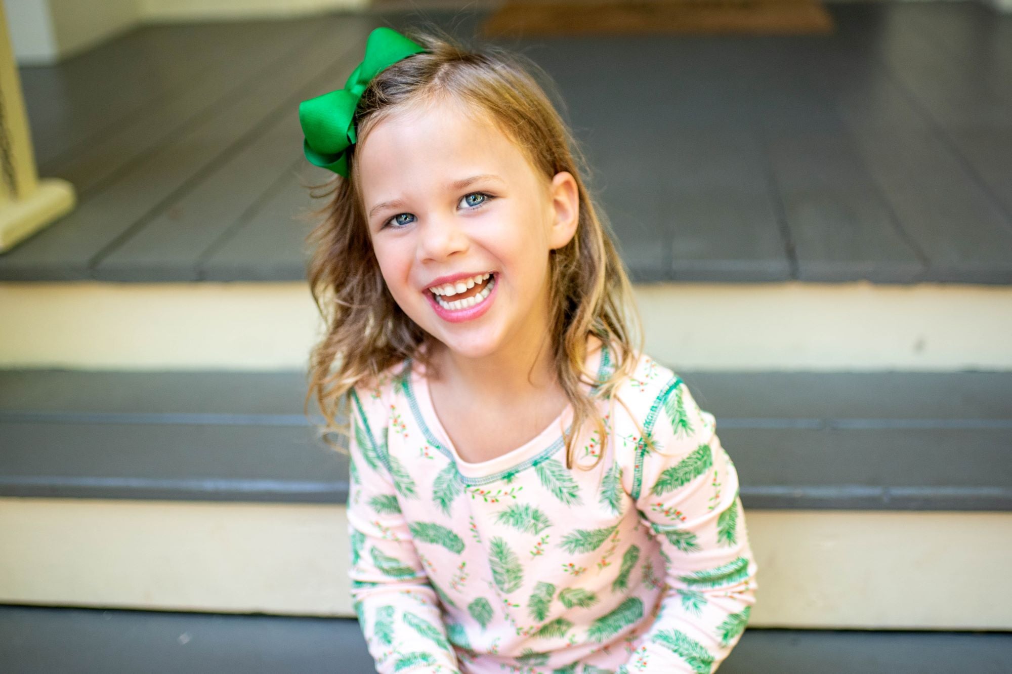 Little Girl wearing Pink two-piece pajama set with vintage Christmas holly pattern made with pima cotton