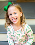 Little Girl wearing Pink two-piece pajama set with vintage Christmas holly pattern made with pima cotton