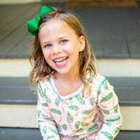 Little Girl wearing Pink two-piece pajama set with vintage Christmas holly pattern made with pima cotton