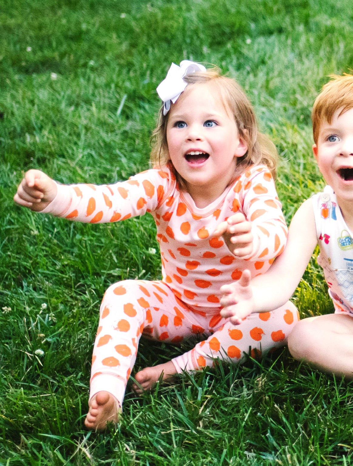 Little Girl Sitting outside in Heyward House 2 Piece Pink and Orange Polka Dot Pajamas