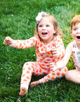 Little Girl Sitting outside in Heyward House 2 Piece Pink and Orange Polka Dot Pajamas