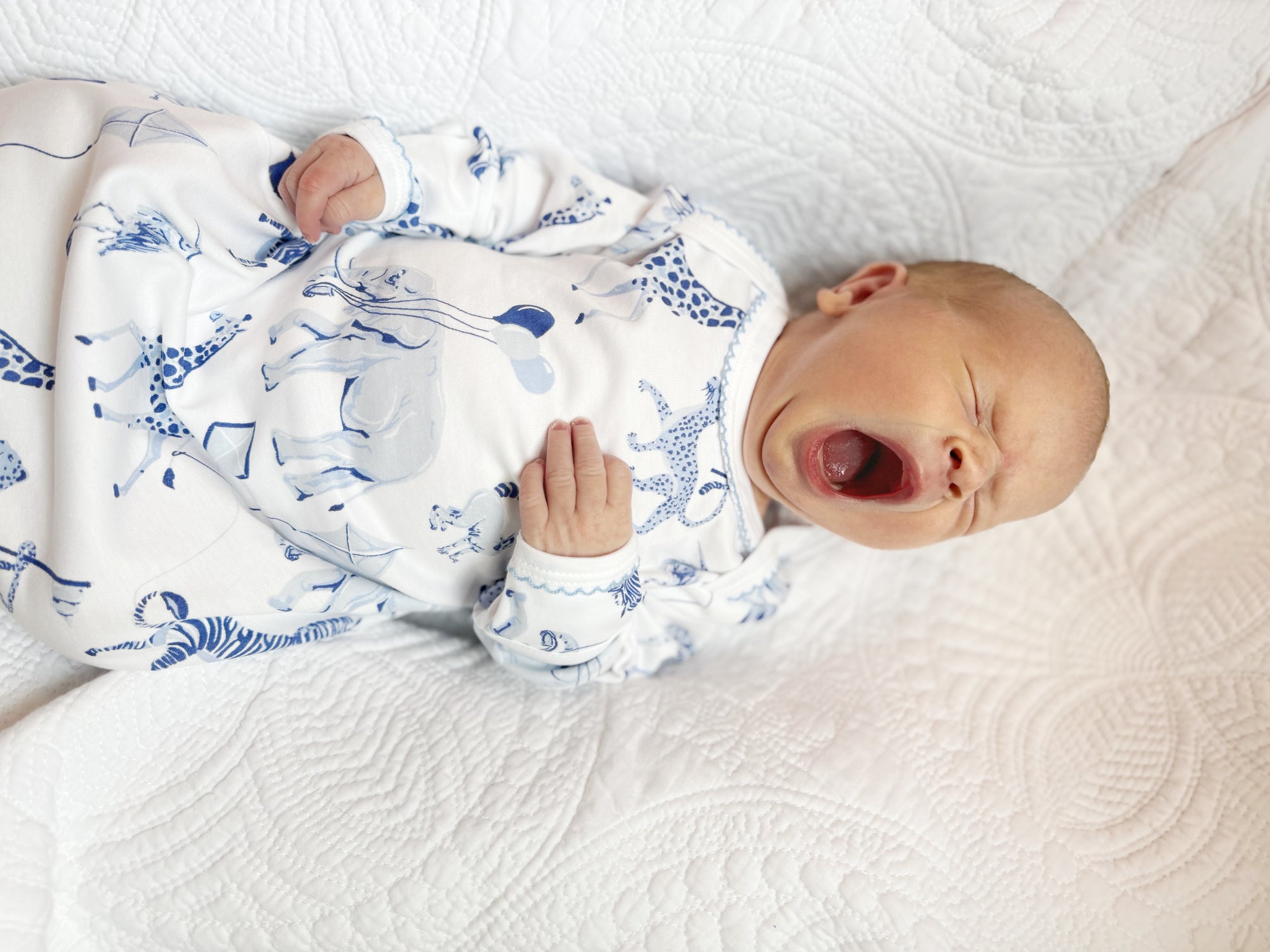 yawning baby in infant gown with blue safari print by Heyward House