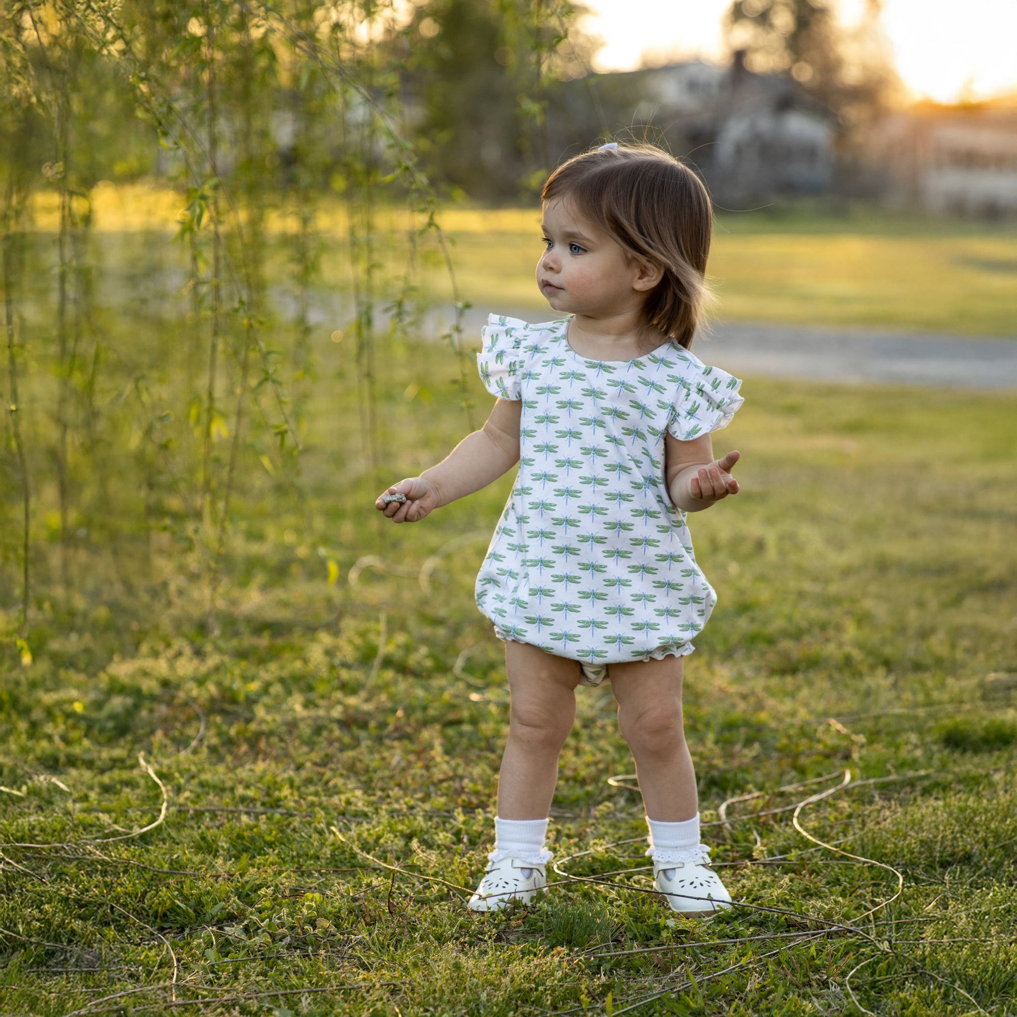 Little girl in field wearing dragonflies bubble in white and green
