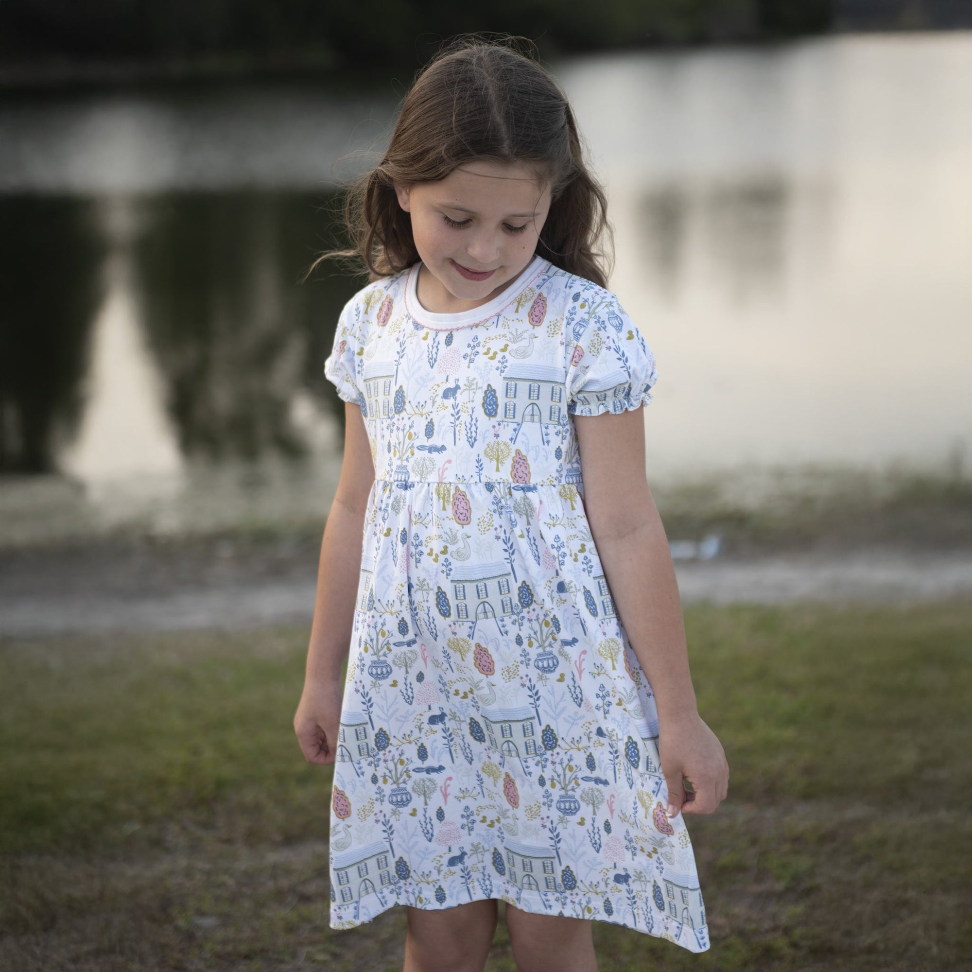 Young girl wearing Heyward House pima play dress with countryside print in mustard and blue colors.