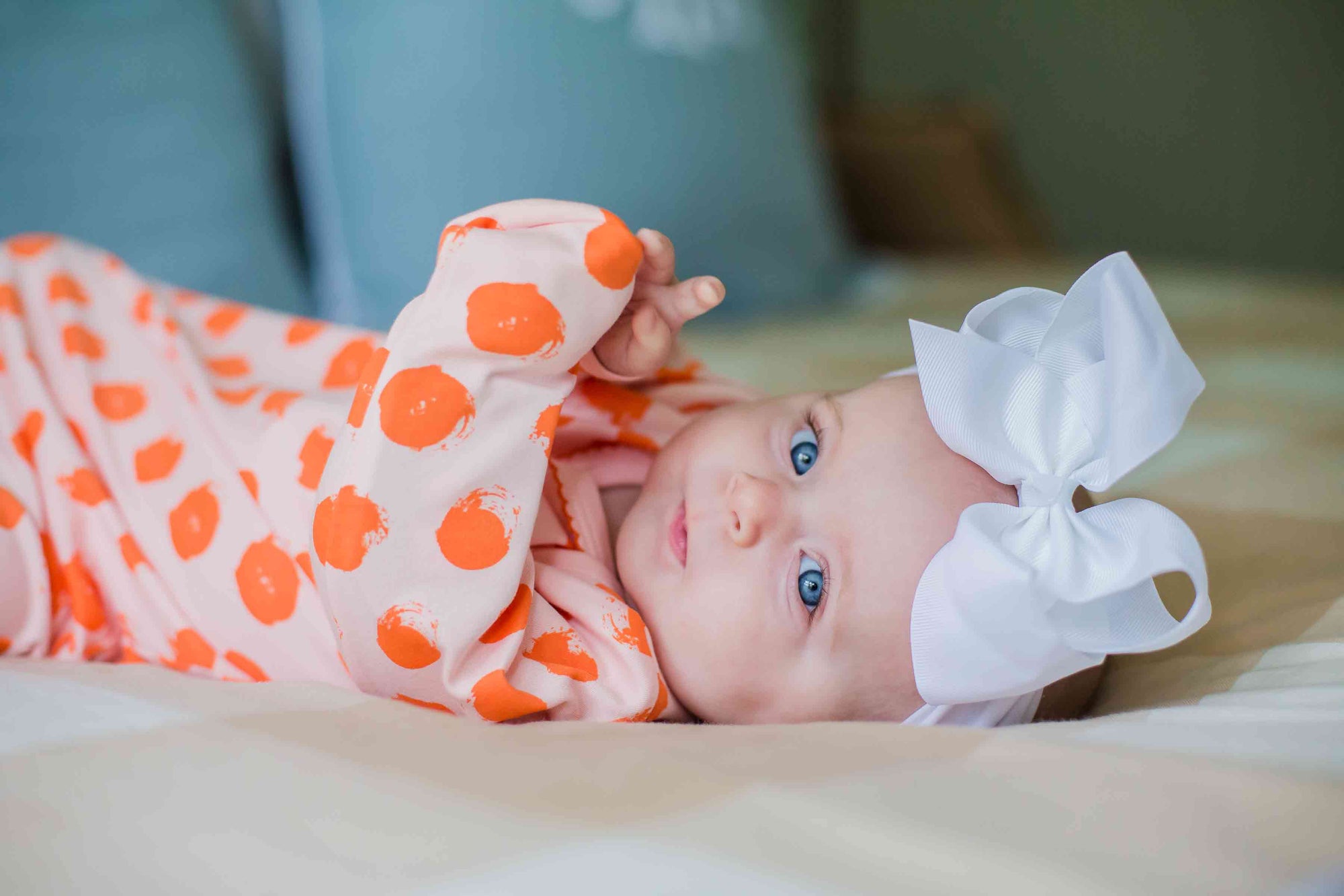 baby-girl-with-blue-eyes-wearing-heyward-house-gown-laying-on-bed