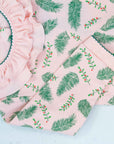 Close-up of pink girls playsuit with classic ruffled collar and vintage Christmas holly pattern made in pima cotton