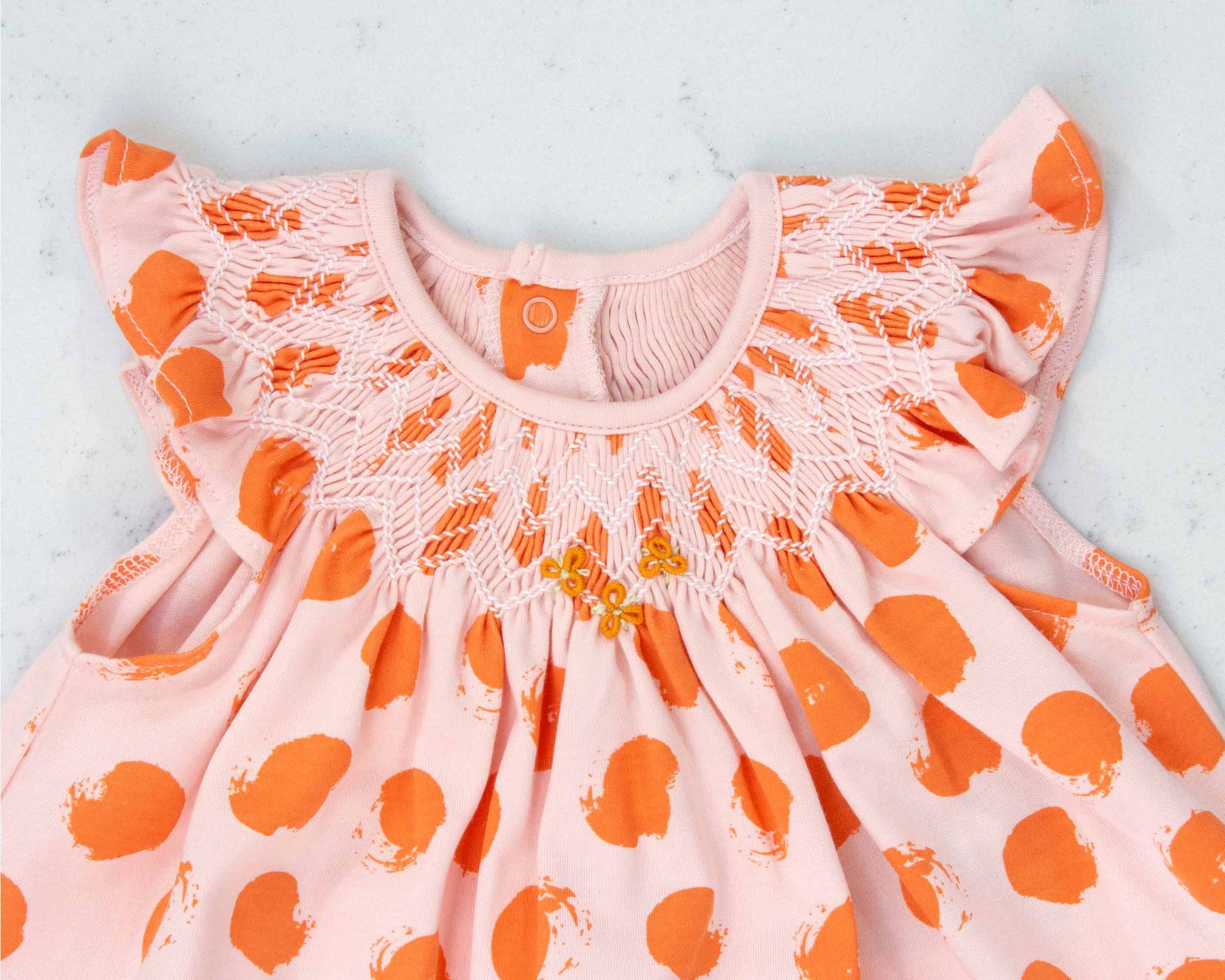 detailed view pink girls dress with smock and orange dots pattern made in pima cotton