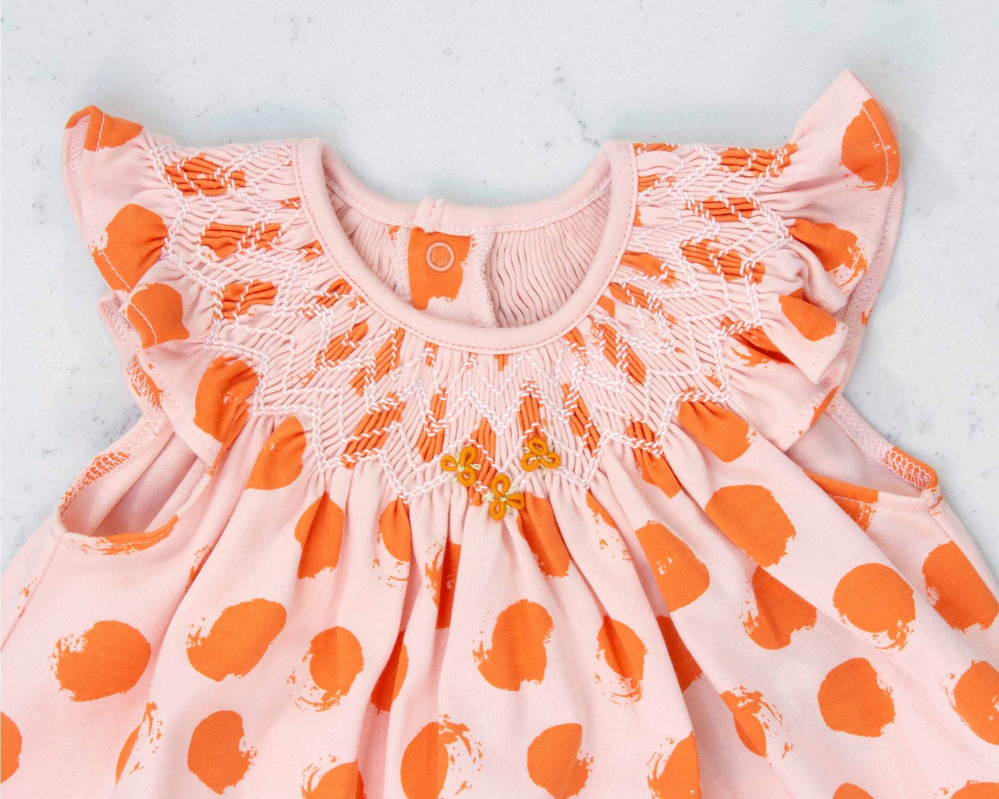 detailed view pink girls dress with smock and orange dots pattern made in pima cotton