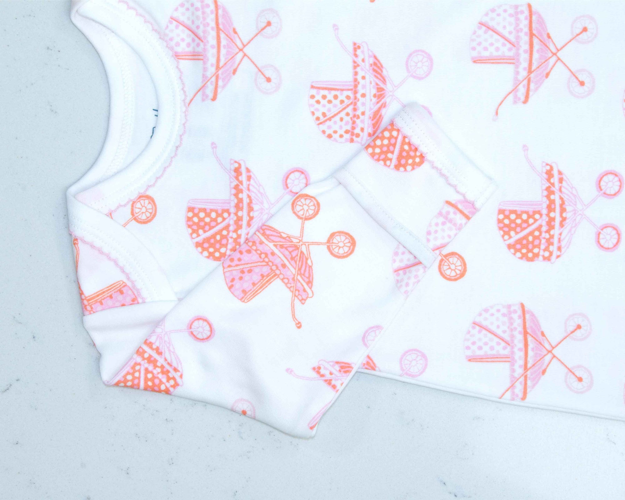 White infant gown with pink baby carriage pram pattern with scratch guard detail
