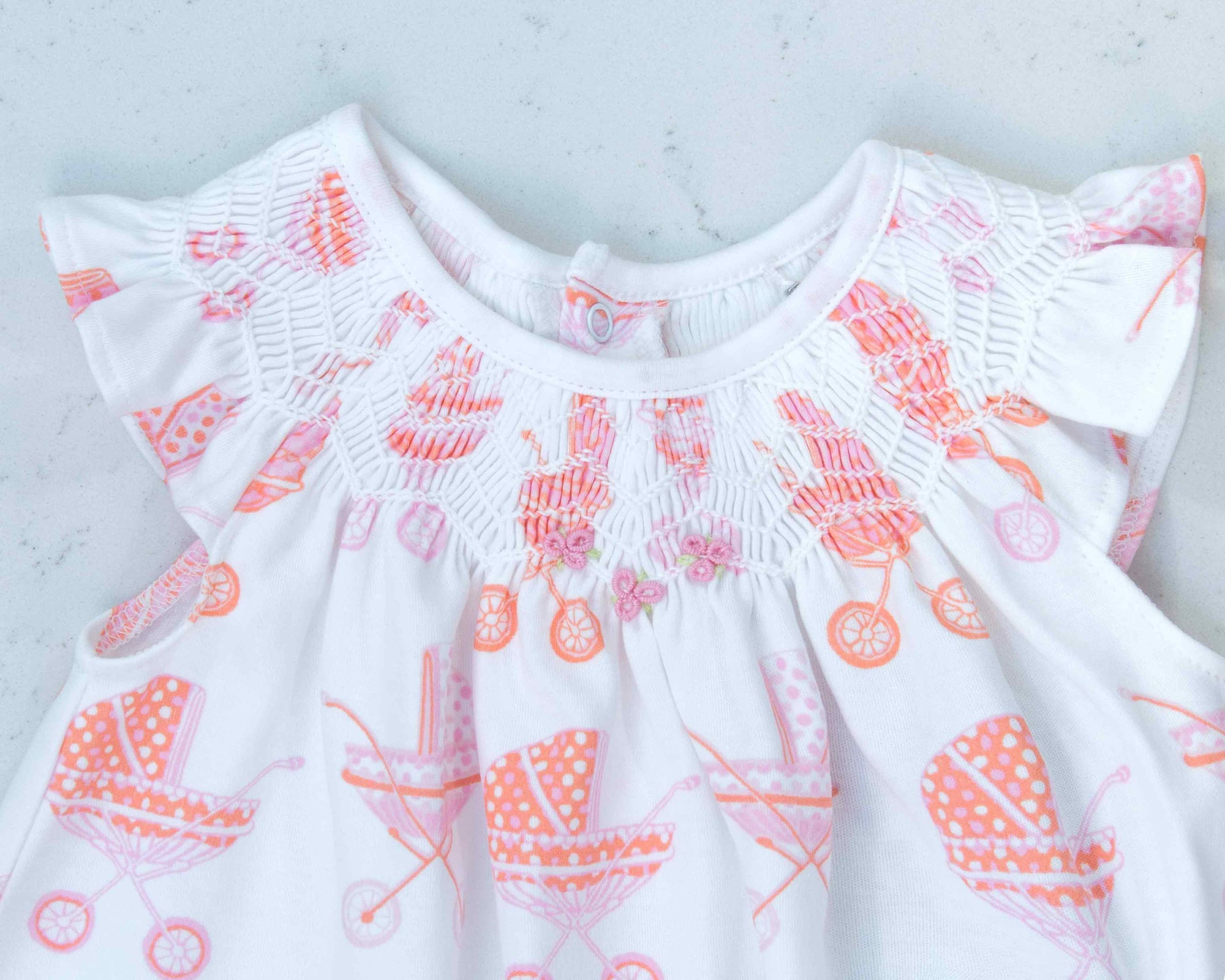 detailed view white girls dress with smock and vintage-inspired baby carriage pattern made in pima cotton