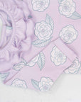 Close-up of pink girls playsuit with classic ruffled collar and camellia flower pattern made in pima cotton
