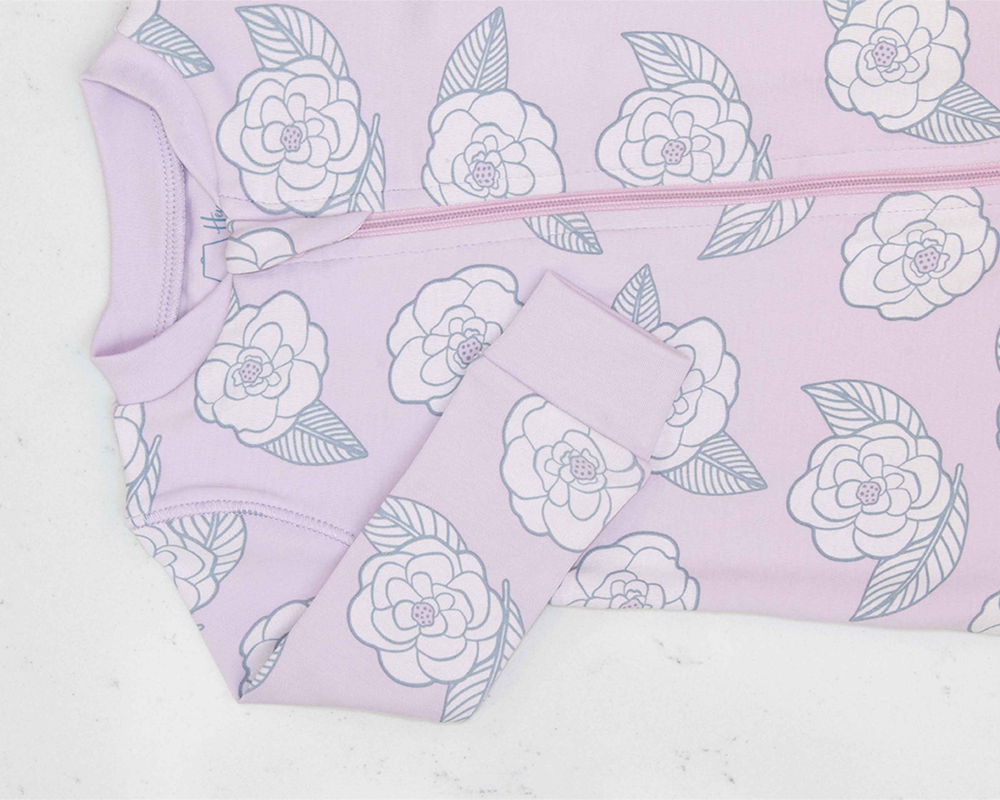 Detail of zipper area of pink footed pajama with camellia flower pattern made in pima cotton