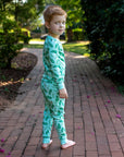 Little Boy Blue wearing two-piece pajama set with vintage Christmas holly pattern made with pima cotton