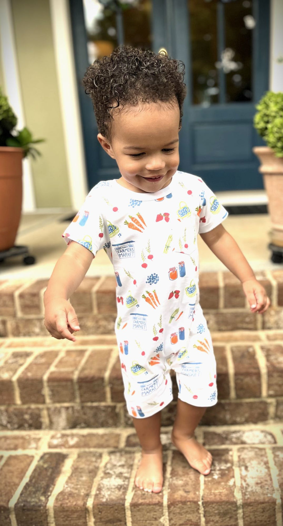 Toddler boy playing in Heyward House Playtime Romper in Farmer's Market pattern