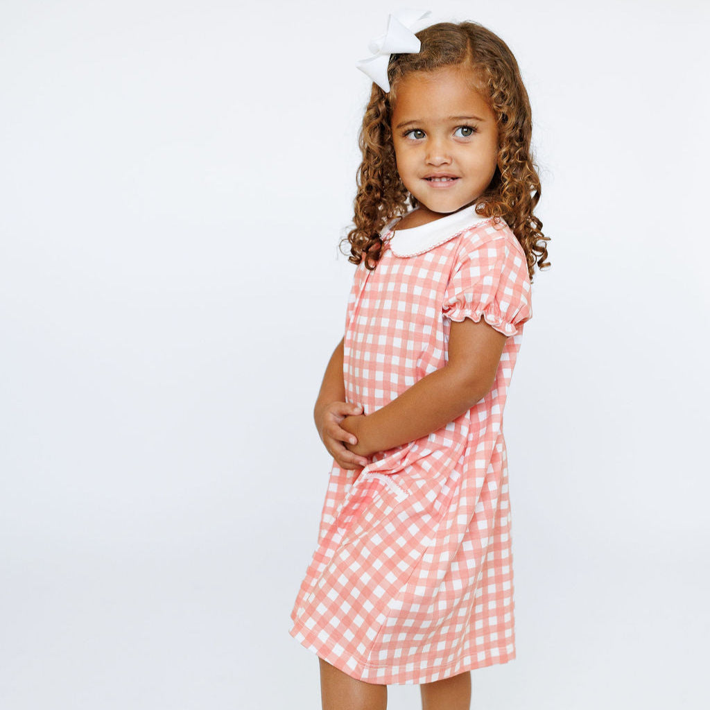 Young girl wearing a pink checkered dress on a white background