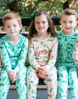 Children wearing Blue and Pink two-piece pajama set with vintage Christmas holly pattern made with pima cotton