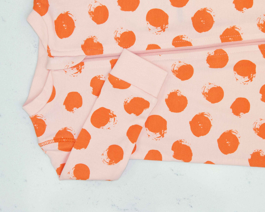 Detail of zipper area of light pink pajama with orange polka-dot pattern made in pima cotton