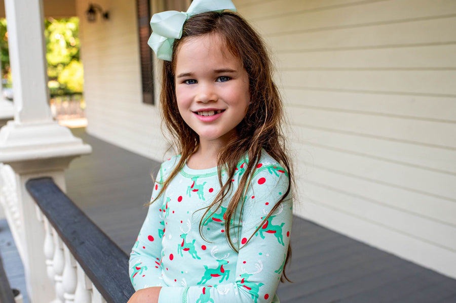Little Girl wearing Mint green two-piece pajama set with vintage Christmas reindeer pattern made with pima cotton