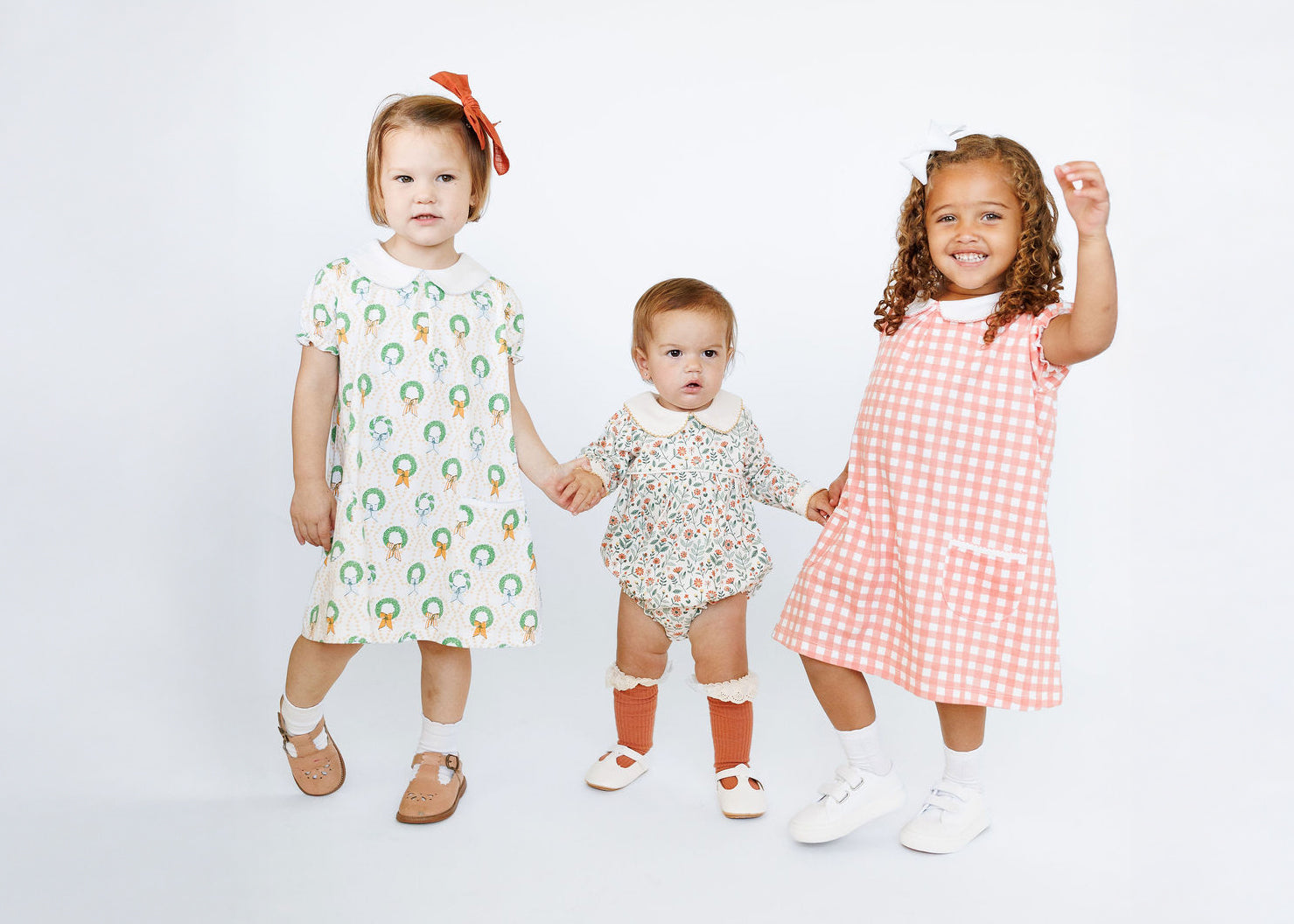 Three children wearing colorful dresses on a white background