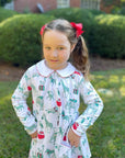 girl wearing safari christmas pocket dress in front of green bushes