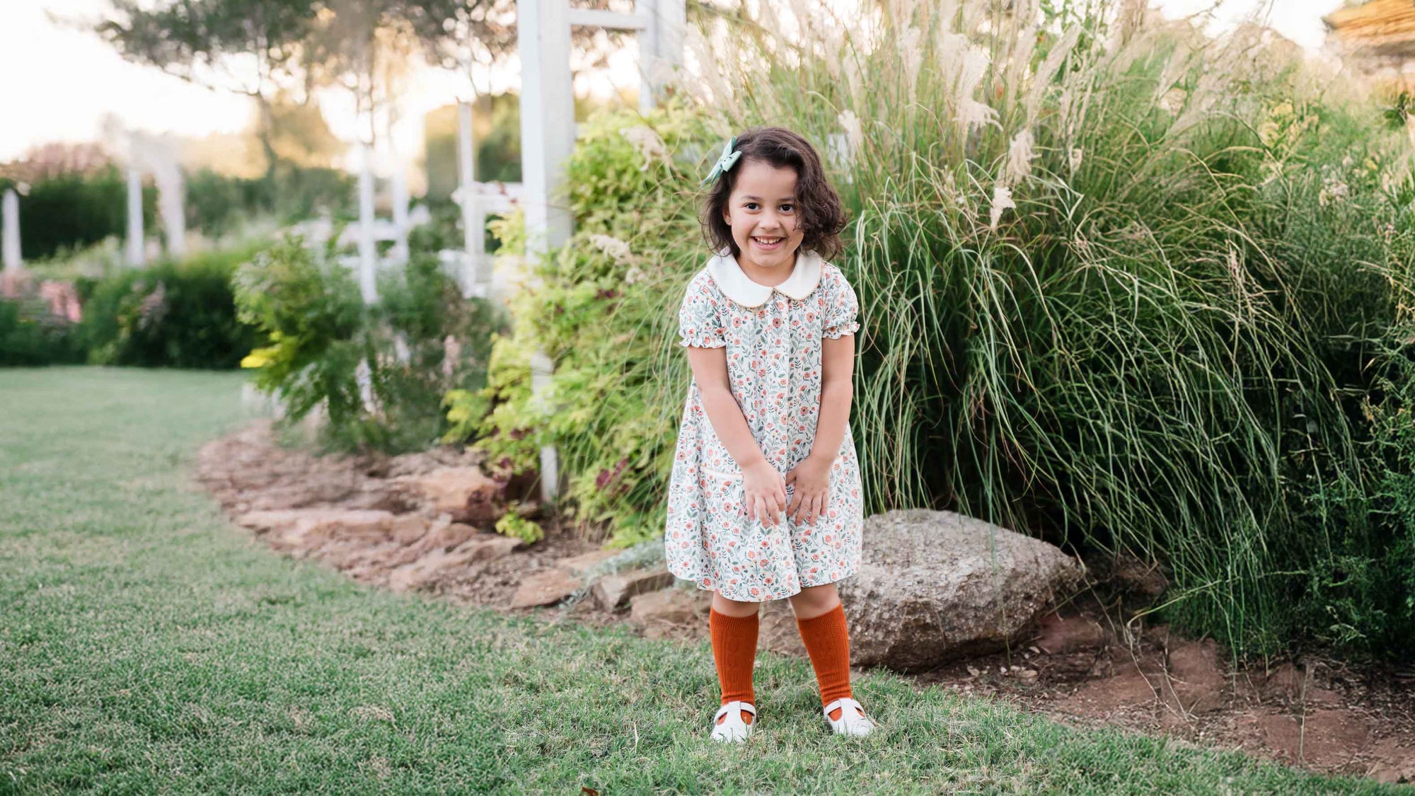 Young girl in a floral dress standing in a garden