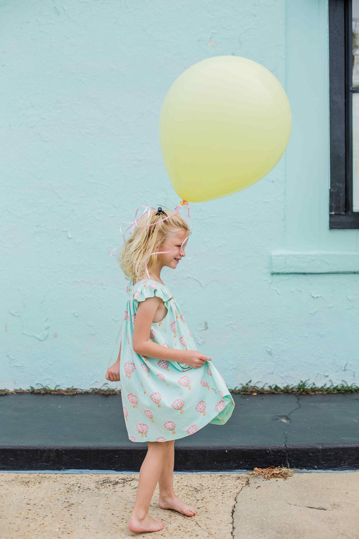 little girl holding yellow balloon wearing heyward house dress with smocking