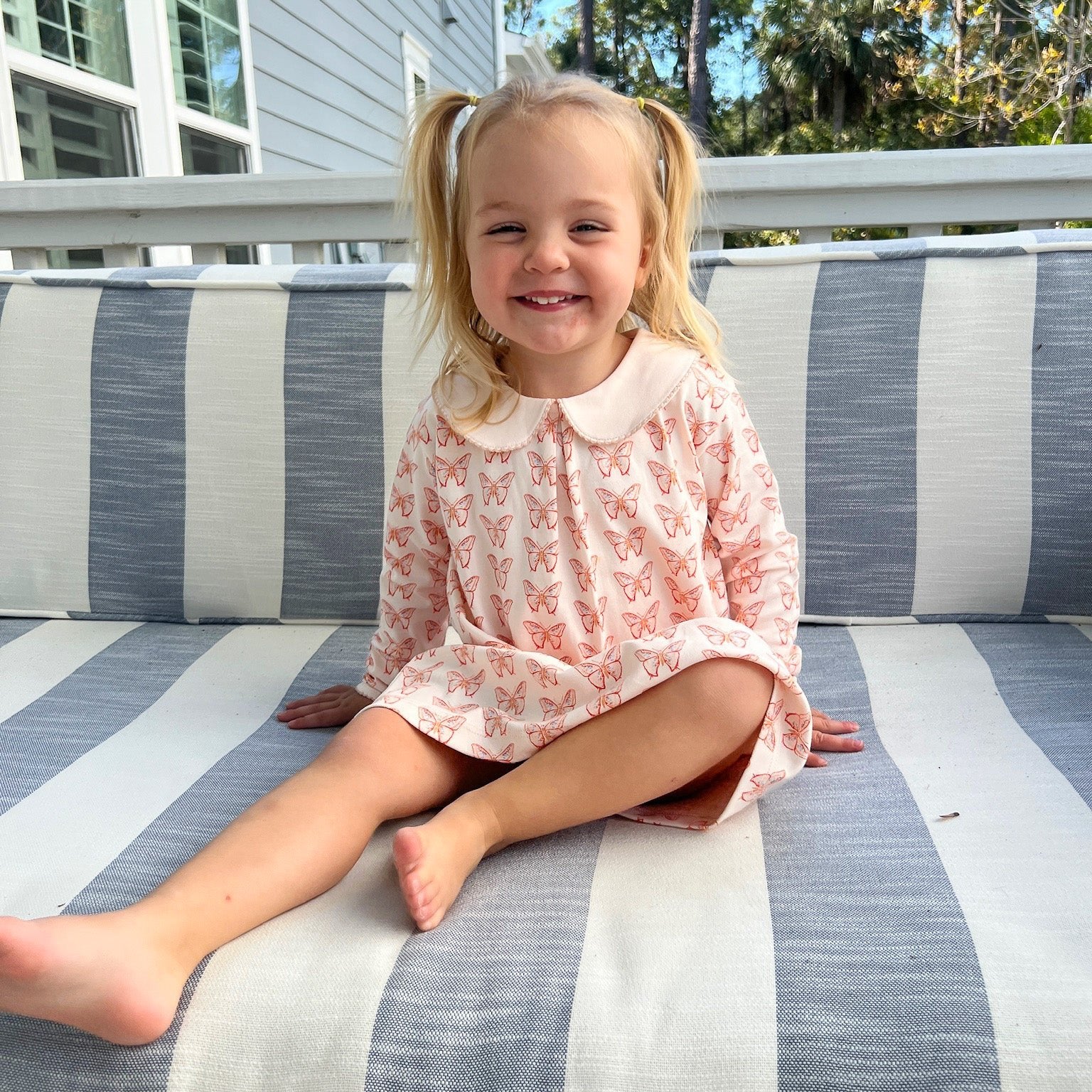 smiling girl wearing pink pima dress with butterfly pattern