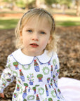 little girl with serious face wearing pima dress with holiday topiary print