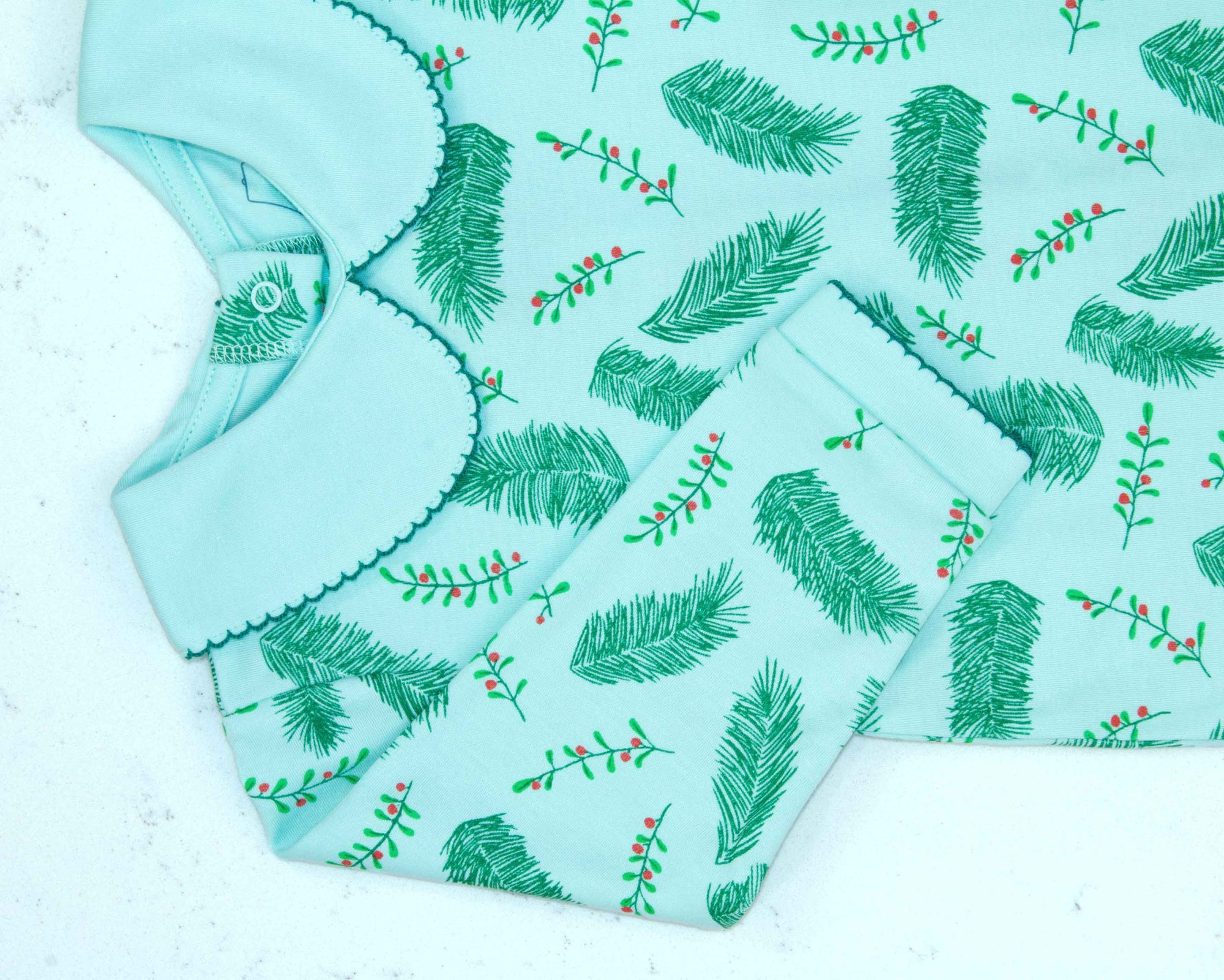Close-up of blue boys playsuit with classic peter-pan collar and vintage Christmas holly pattern made in pima cotton