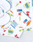 Close-up of white boys playsuit with classic peter-pan collar and fruit and vegetable pattern made in pima cotton