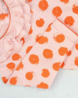 Close-up of pink girls playsuit with classic ruffled collar and orange dots pattern made in pima cotton