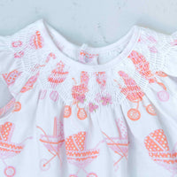 detailed view white girls dress with smock and vintage-inspired baby carriage pattern made in pima cotton