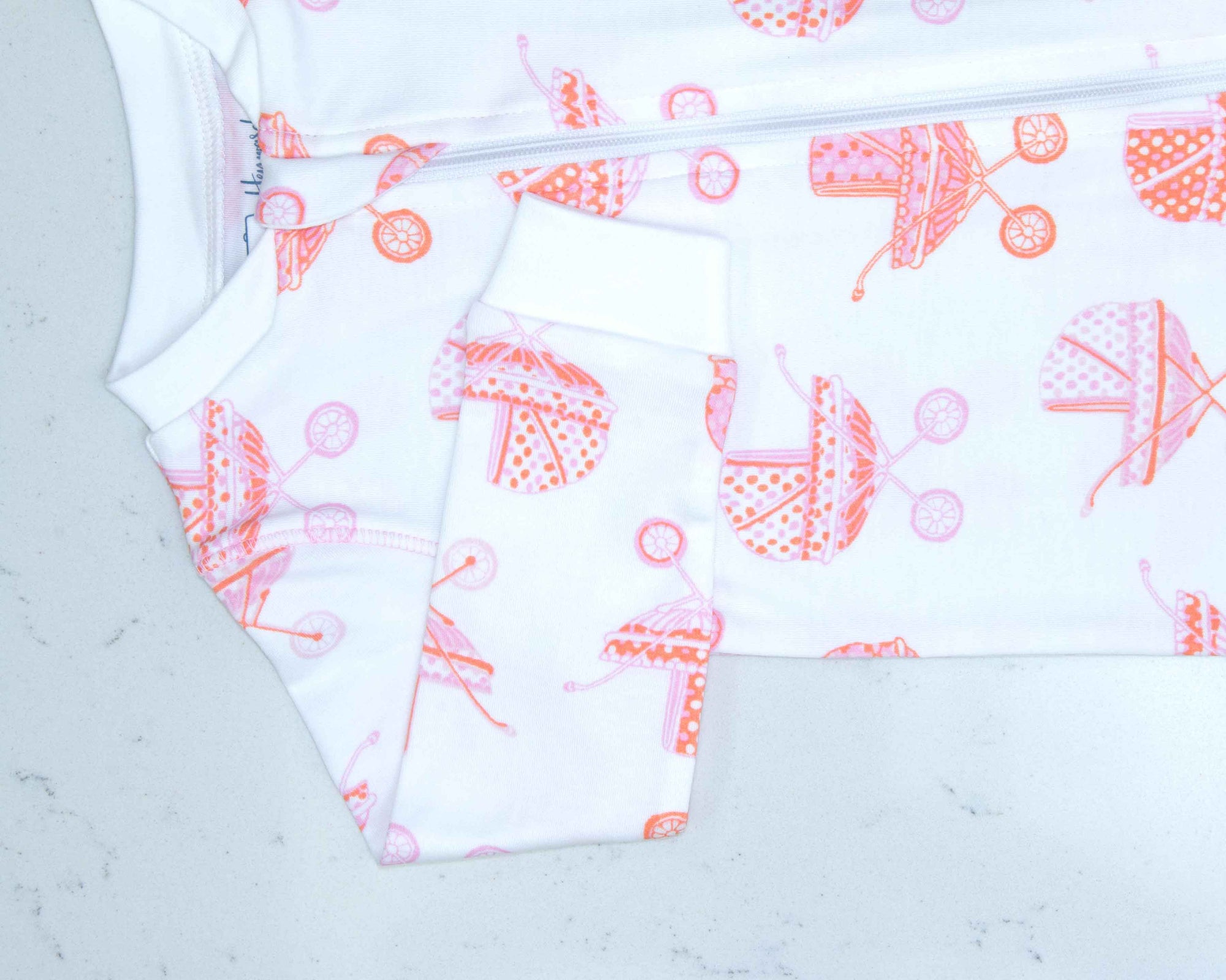 Detail of zipper area of white footed pajama with vintage baby carriage pattern made in pima cotton