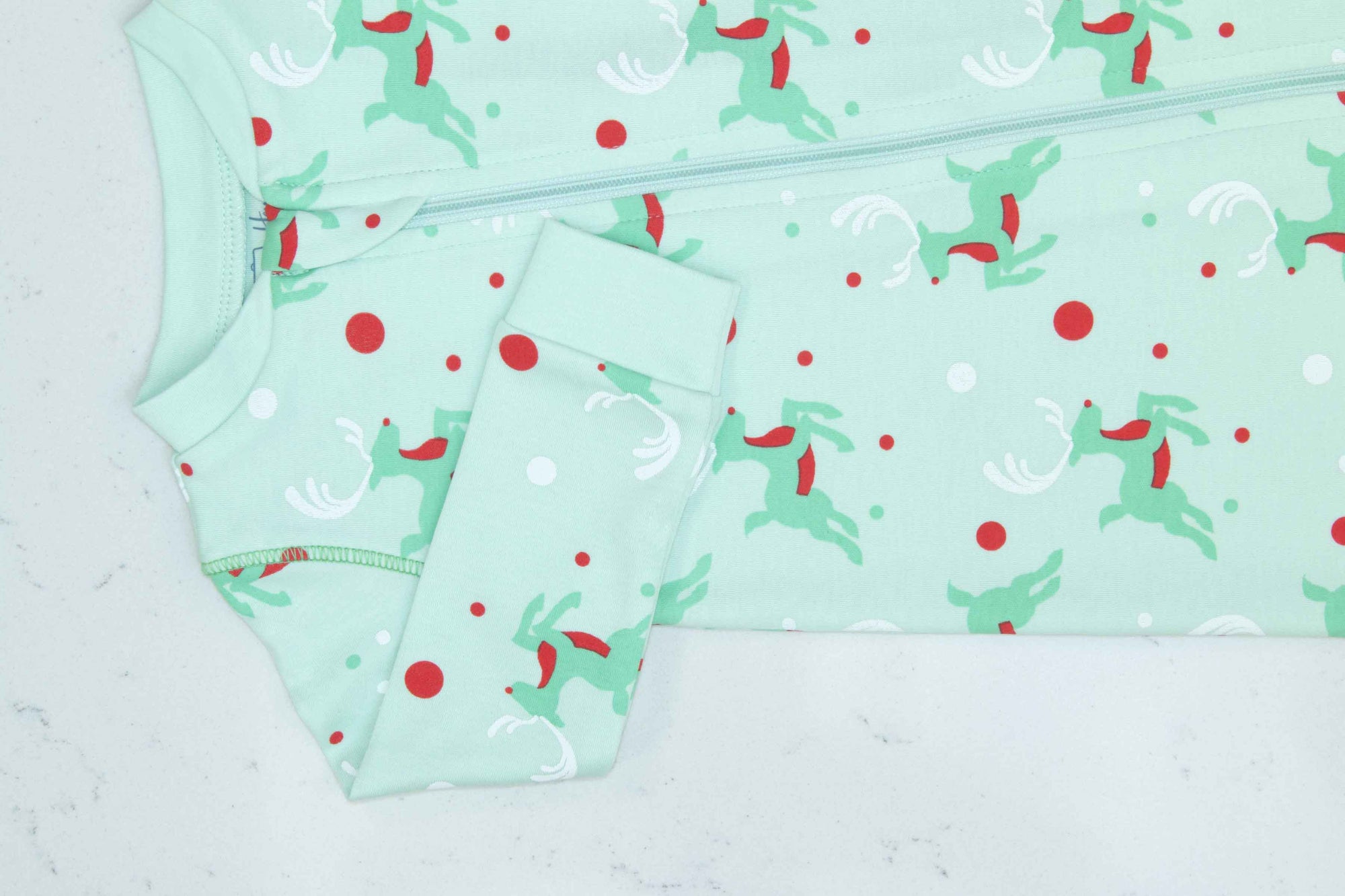 Detail of zipper area of mint green footed pajama with Christmas Reindeer pattern made in pima cotton